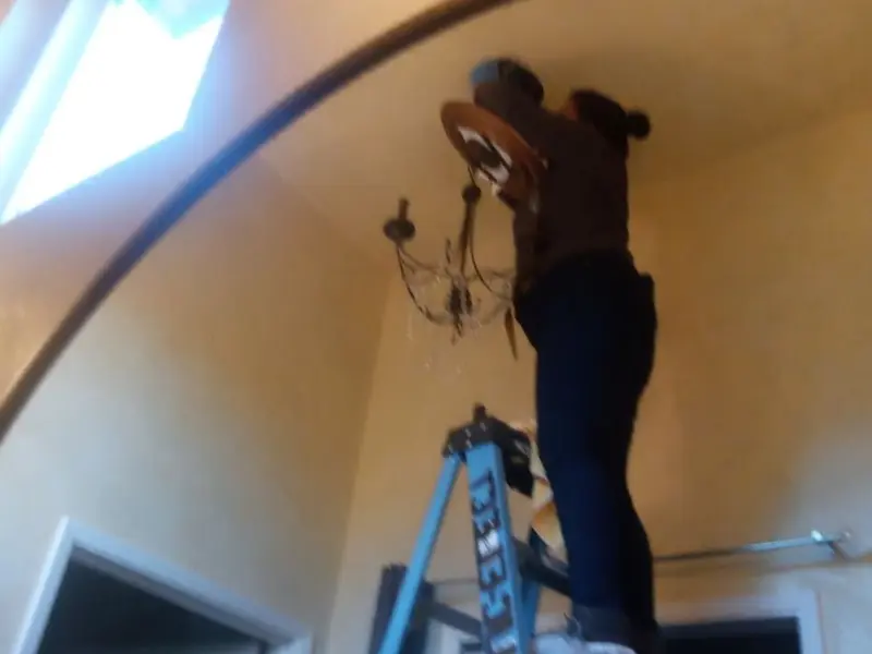Electrician installing a chandelier in a Hampton residence